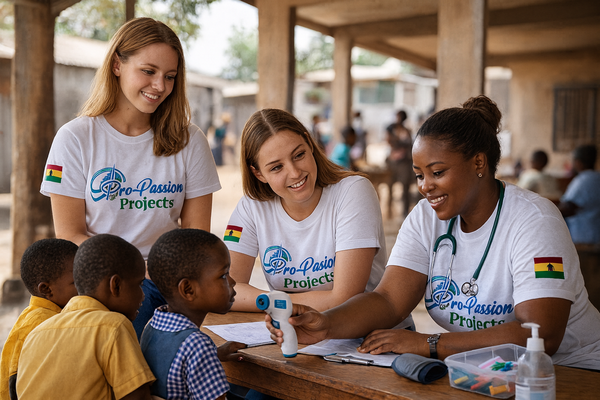 Two white nursing volunteers provide basic health checks and guidance to a group of Ghanaian school children at a local school, under the supervision of a professional medical coordinator. This image represents the hands-on, community-focused approach of